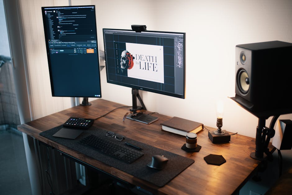 A modern home office setup with dual monitors, keyboard, mouse, and speakers on a wooden desk.