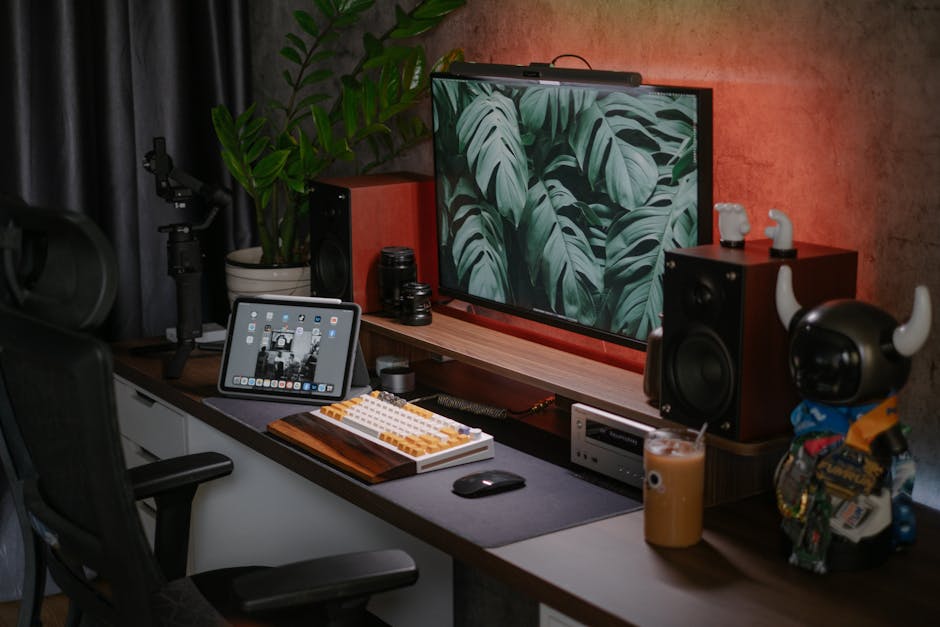 A stylish home office setup featuring a monitor, tablet, speakers, and decorative items.